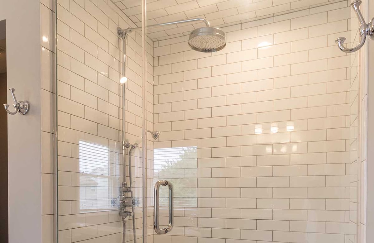 closed up view of backsplash tiles and shower head in a bathroom remodeled by Hogan Design and Construction