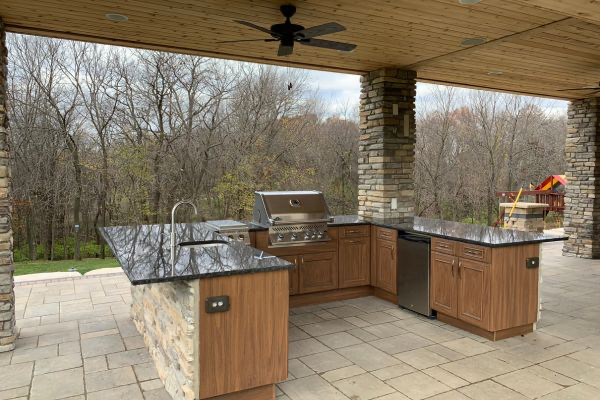 Outdoor Kitchen on a stone patio with a gas grill, running water, and prep station