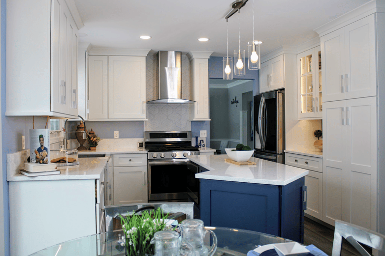 Kitchen remodel featuring white cabinetry with a contrasting blue island, white quartz counters throughout.