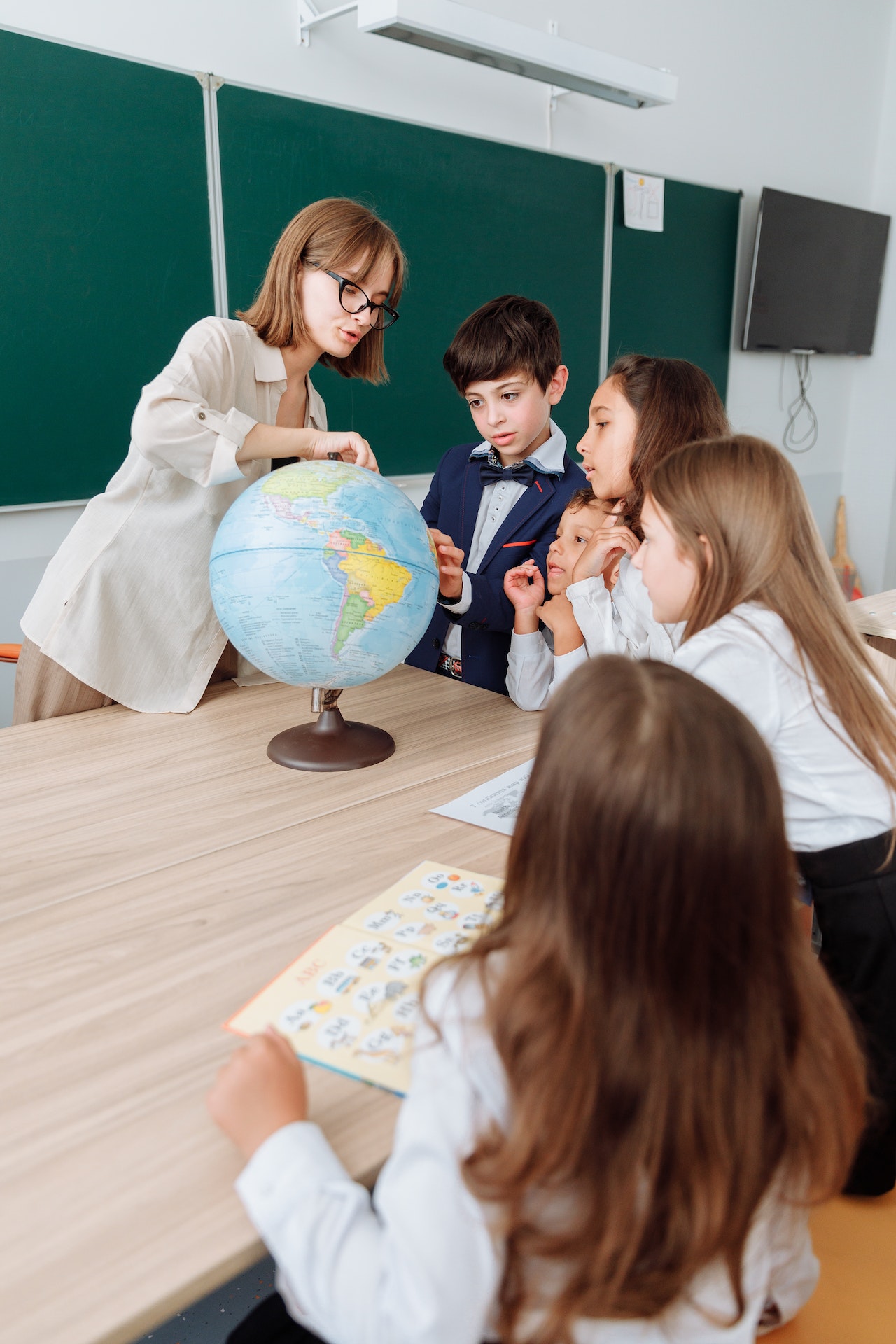 Teacher with students surrounding a globe